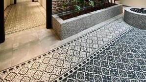 A modern hotel lobby with a stone wall, a wooden sign, and a patterned floor.