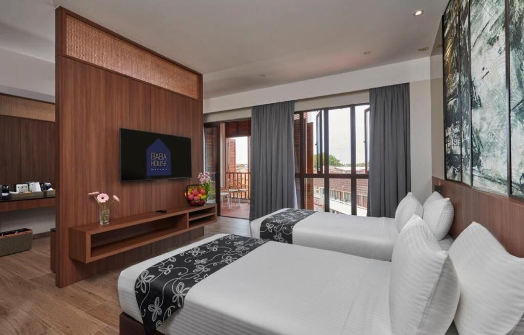 A hotel room with two beds, a TV, a balcony with a view, and a large painting.