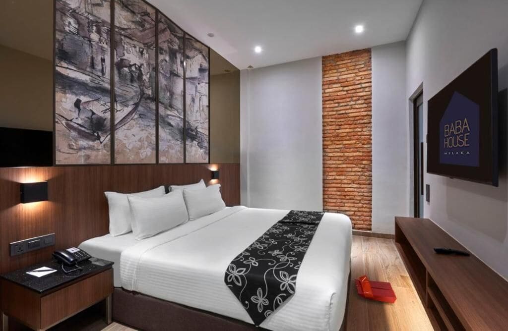Una habitación de hotel moderna con una cama grande, un cabecero de madera, un televisor de pared y una pared decorativa de ladrillo.