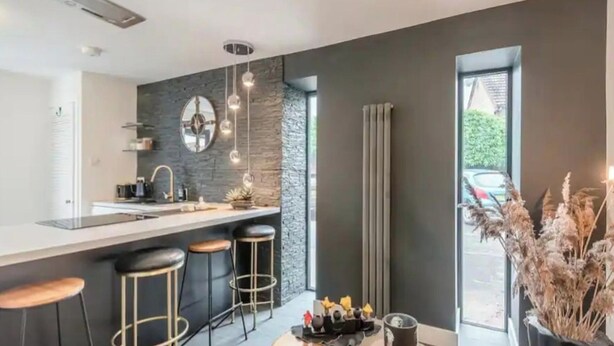A modern kitchen with a central island, bar stools, a large window, and a view of the outdoors. - 1 Bed Barn Retreat - Fireplace, Patio, Parking (Lincoln)