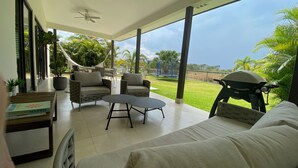 Un amplio patio con un sofá, dos sillones y una mesita.