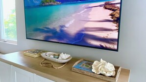 Un televisor de pantalla plana montado en la pared sobre un mueble de madera con una bandeja de objetos decorativos.