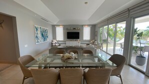 Un comedor moderno con una mesa de vidrio, sillas de mimbre y un televisor de pantalla plana sobre la encimera.