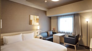 Une chambre d’hôtel avec un grand lit, un bureau, une chaise, un canapé et une lampe.