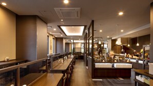 Un restaurant moderne avec un intérieur comprenant de longues tables communes, des espaces individuels et un buffet.