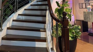 A modern staircase with a glass railing, wooden steps, and a geometric wall design. - Seacliff Suites Hotel & Resort (Pinamalayan)