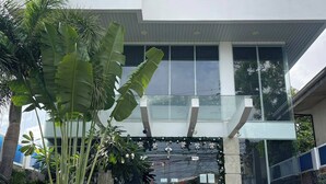 A modern building with a glass entrance, surrounded by tropical plants. - Seacliff Suites Hotel & Resort (Pinamalayan)