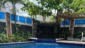 A swimming pool with a stone wall and blue-tiled edge. - Seacliff Suites Hotel & Resort (Pinamalayan)