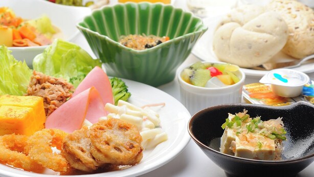 A table with various dishes including fried items, a bowl of salad, and a glass of orange juice. - Hotel Route Inn Grand Kainan Ekimae (Kainan)