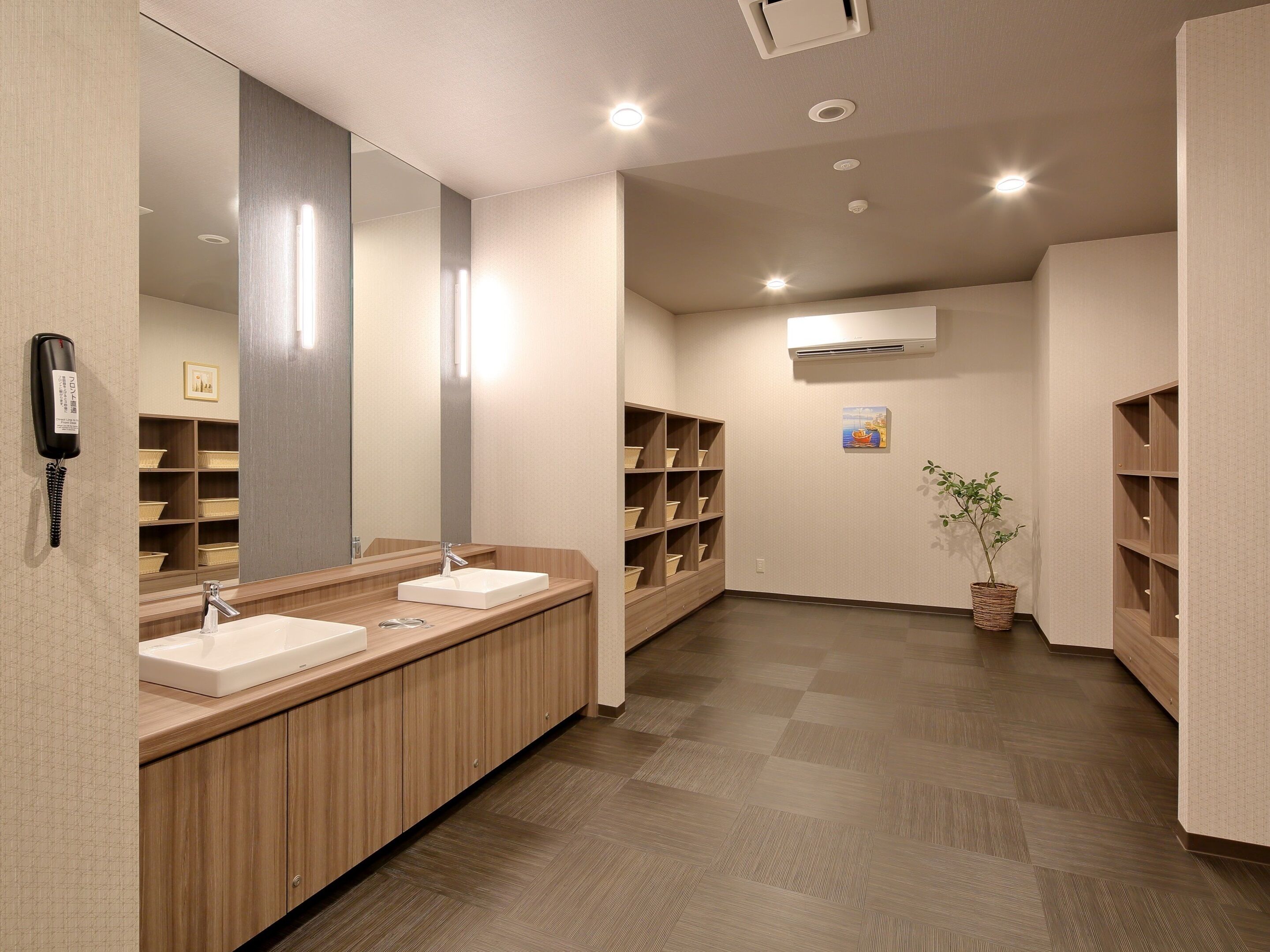 A modern bathroom with two sinks, a large mirror, and wooden shelving.