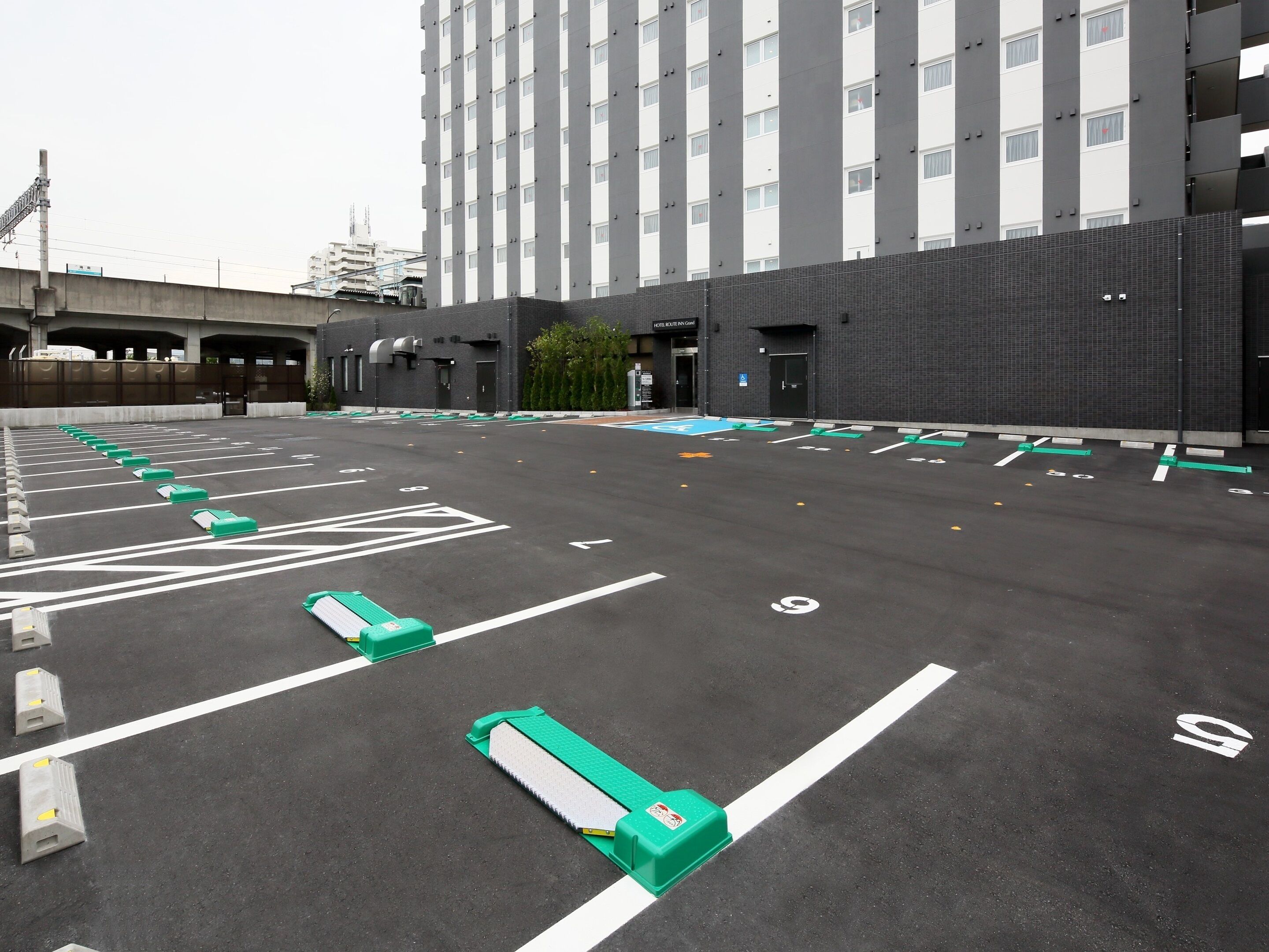 A parking lot with marked spaces and green barriers.