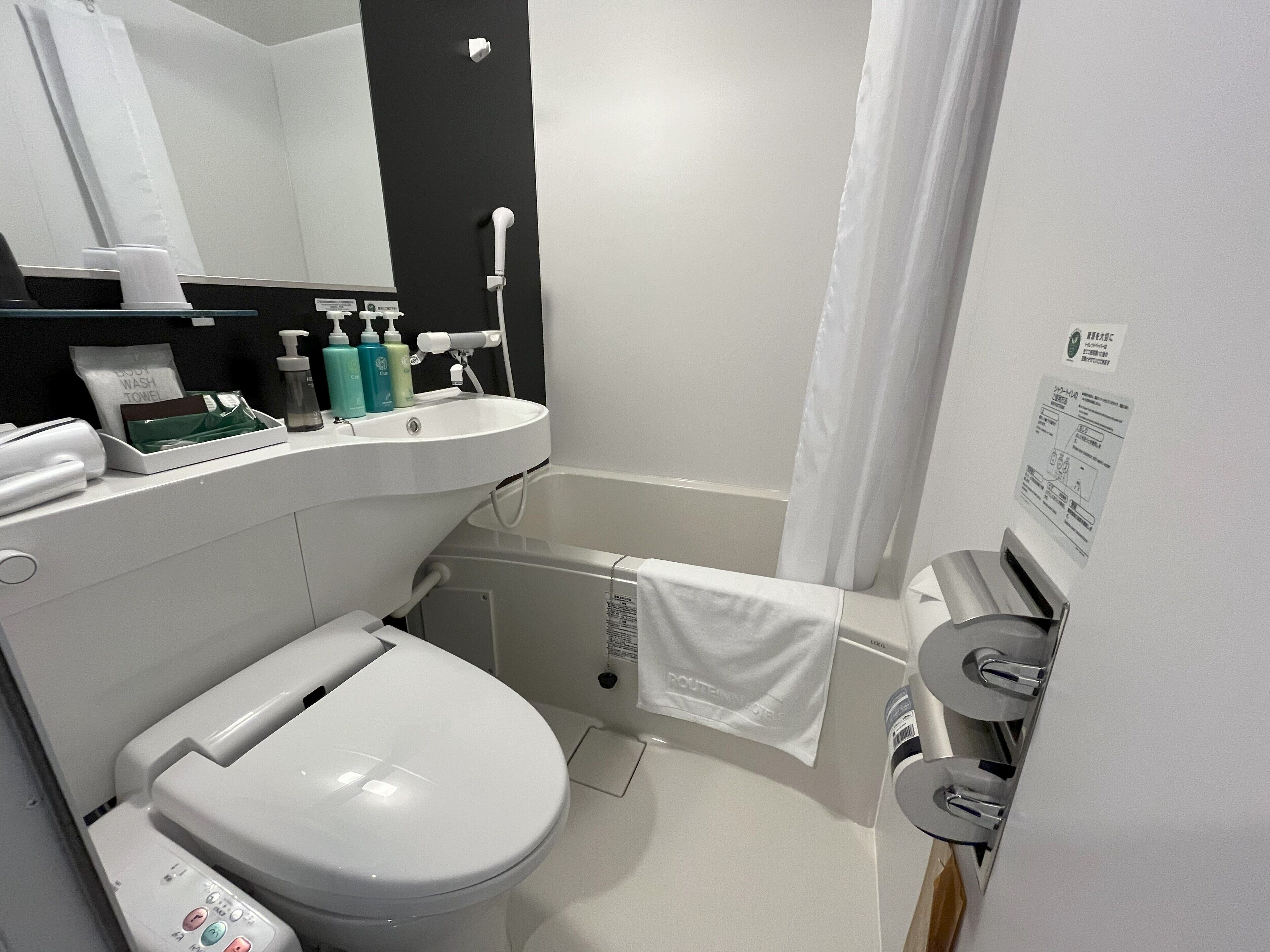 Een moderne badkamer met toilet, wastafel en douche.