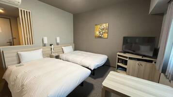 Een hotelkamer met twee bedden, een televisie, een bureau en een spiegel.
