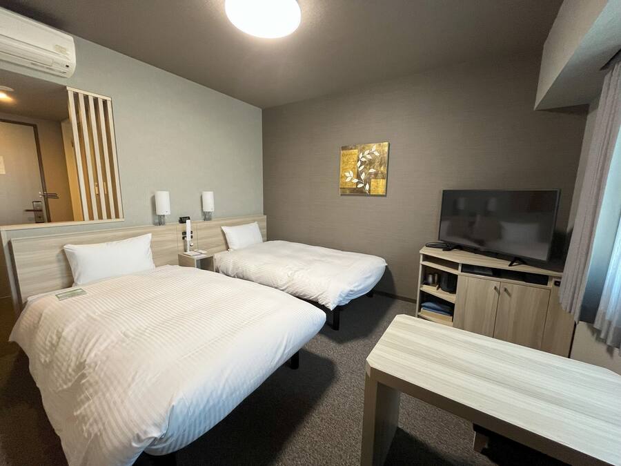 Een hotelkamer met twee bedden, een televisie, een bureau en een spiegel.