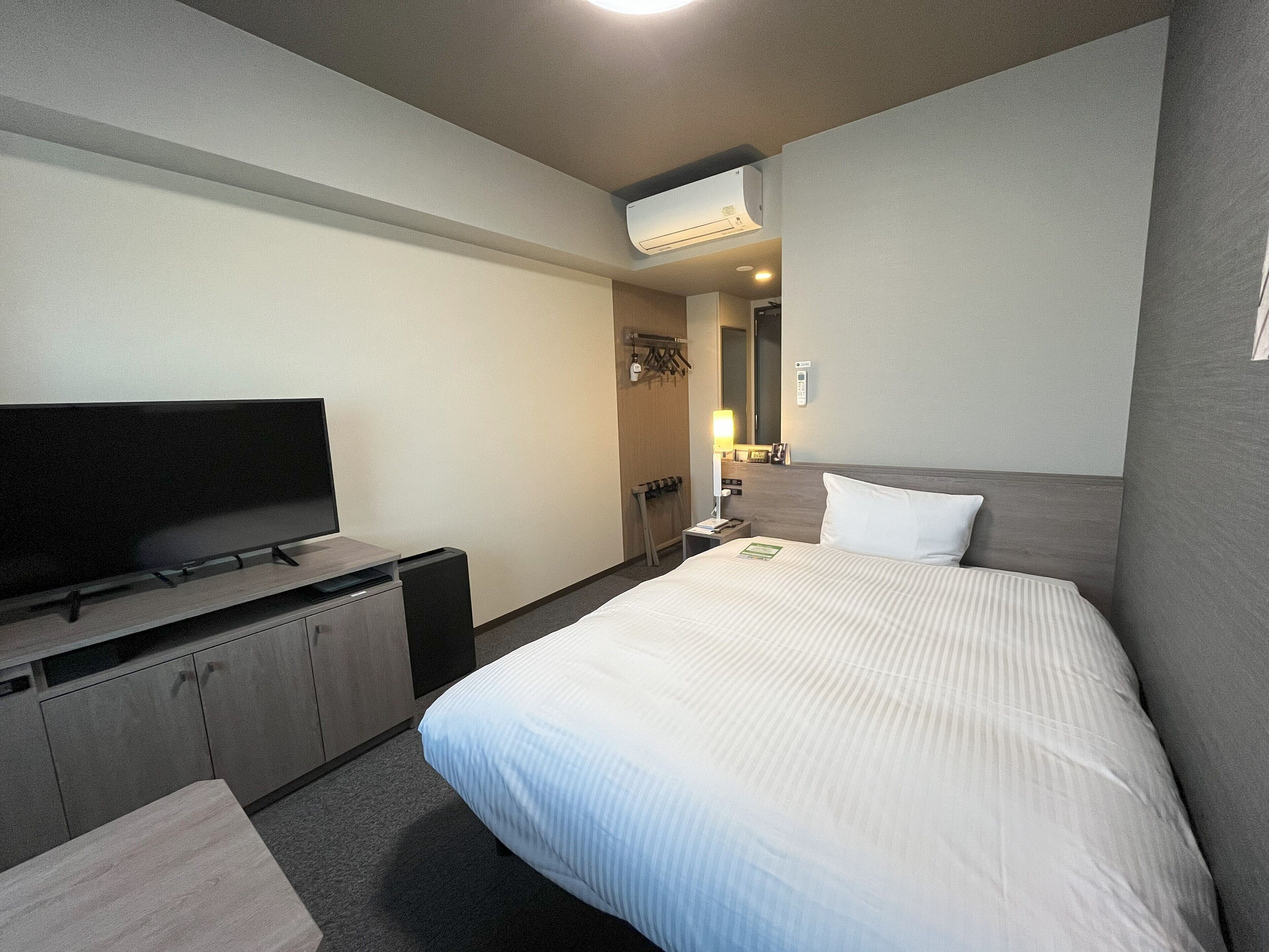 A hotel room with a bed, a TV, a desk, and a wardrobe.