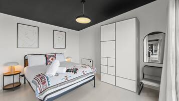 Un dormitorio moderno con cama, lámparas de noche, armario y espejo.