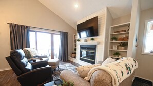 Ein modernes Wohnzimmer mit Kamin, Flachbildfernseher und einer gemütlichen Sitzecke.