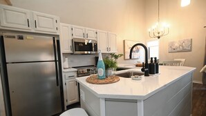 Eine moderne Küche mit weißen Schränken, Edelstahlgeräten und einer zentralen Kochinsel.