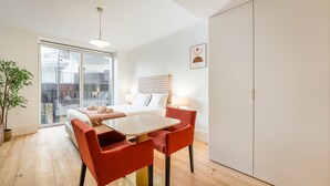 Quarto moderno com cama, mesa de jantar, cadeiras, um vaso de planta e um guarda-roupa.