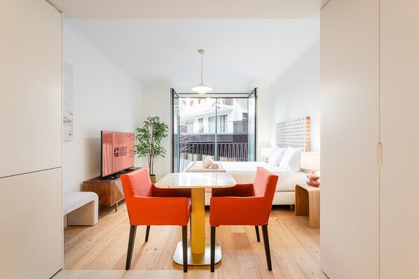 Une chambre d’hôtel moderne dotée d’un coin repas, d’une télévision, d’une plante et d’un balcon avec vue.