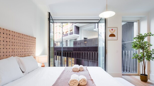 Une chambre d’hôtel moderne avec un grand lit, une vue sur un balcon et une plante en pot.