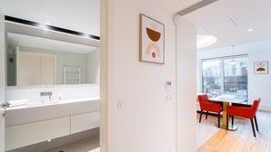 Une salle de bain moderne avec un grand miroir, des meubles blancs et une cabine de douche en verre.