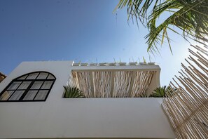A white building with a large arched window and a series of plants on the roof. - Villa Tora Canggu (Canggu)