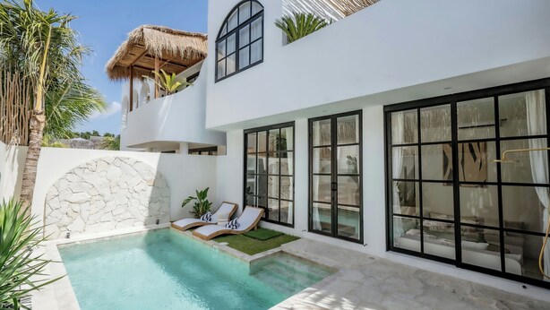 A modern villa with a swimming pool, large windows, and a stone wall. - Villa Tora Canggu (Canggu)