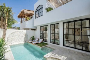 Eine moderne Villa mit Swimmingpool, großen Fenstern und einer Steinmauer.