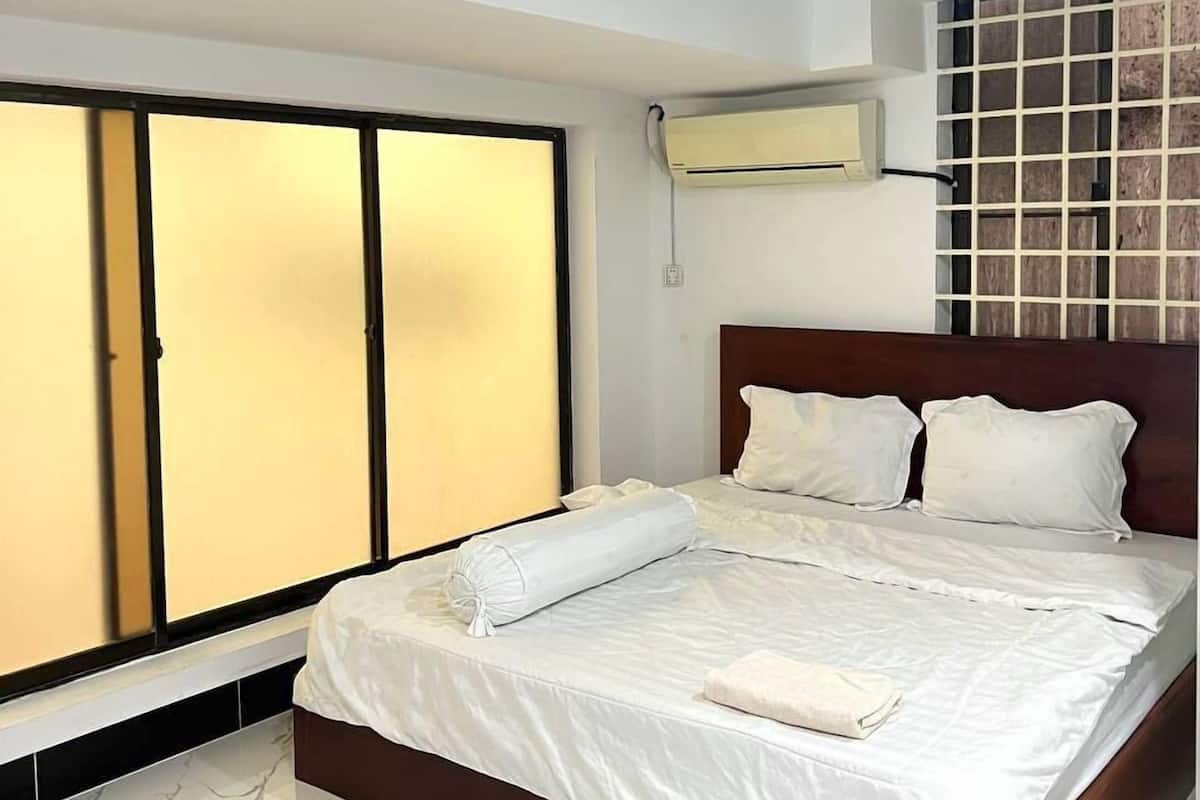 A hotel room with a bed, a wardrobe, and a wall-mounted air conditioner.