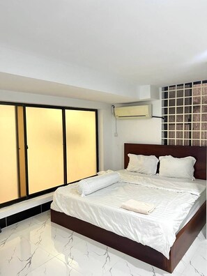 A hotel room with a bed, a wardrobe, and a wall-mounted air conditioner. - Jasminsorium (Phnom Penh)