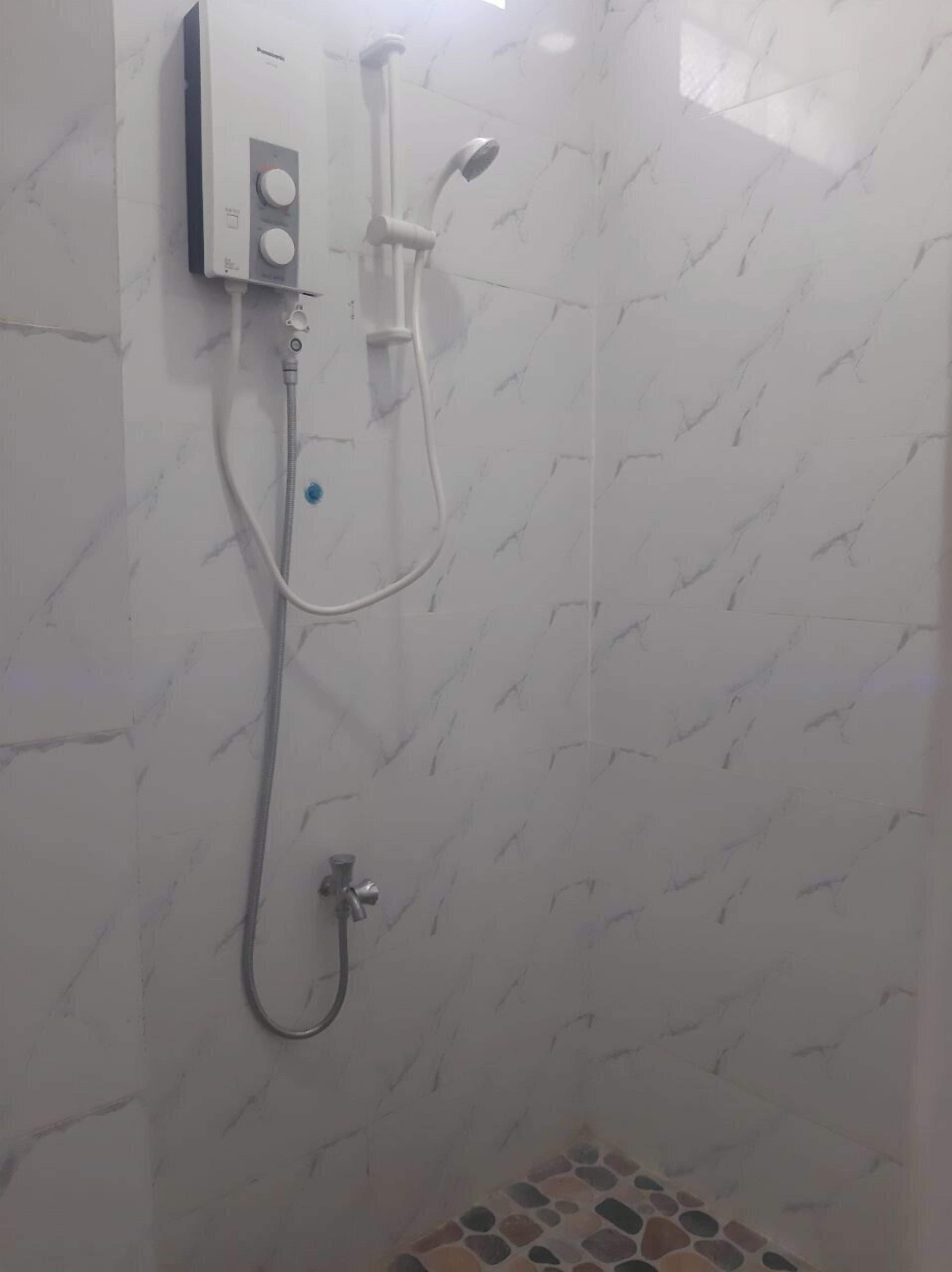 A bathroom with a wall-mounted shower unit, a handheld showerhead, and a handheld faucet.