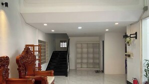 A spacious room with a wooden sofa set, a staircase, and a fire extinguisher. - Jasminsorium (Phnom Penh)