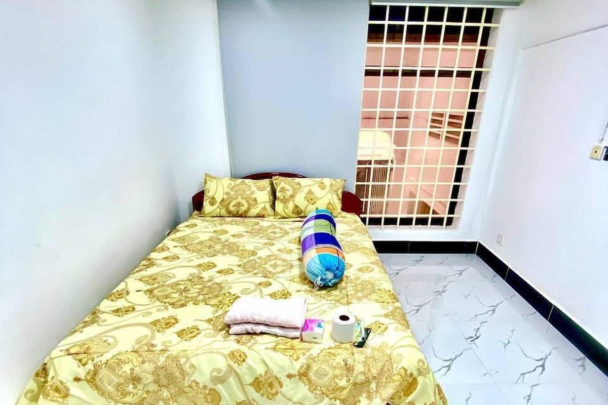A bedroom with a bed, a window with bars, and a marble floor.