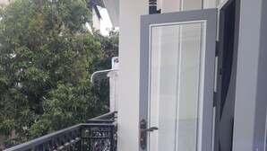 A balcony with a metal railing, a glass door, and a tiled floor. - Jasminsorium (Phnom Penh)