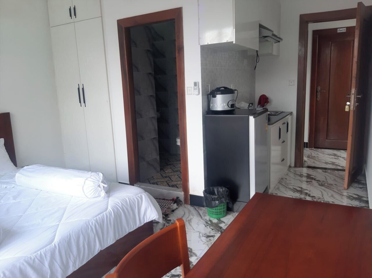 A room with a bed, a small kitchenette, and a door leading to another room.