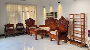A living room with a sofa set, two armchairs, a coffee table, and a wooden bookshelf. - Jasminsorium (Phnom Penh)