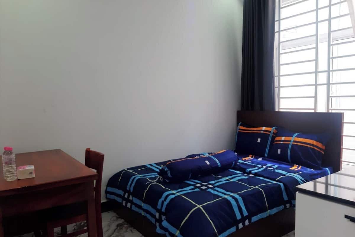 A small, neatly arranged room with a bed, a table, and a chair.