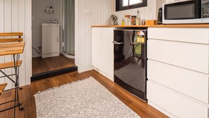 A compact kitchen with a microwave, a small refrigerator, and a wooden countertop.