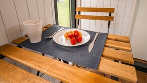 A table with a plate of waffles and strawberries, a white mug, and cutlery on a dark placemat.