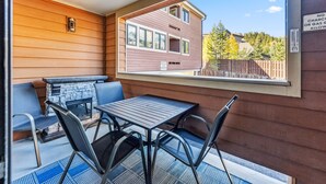 A covered patio with a stone fireplace, metal chairs, and a table. - Steps to Gondola, Ski-In, 1 Block Main St, Hot Tub (Breckenridge)