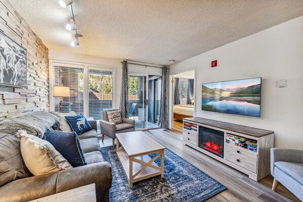 A modern living room with a fireplace, a large TV, and a comfortable seating area.