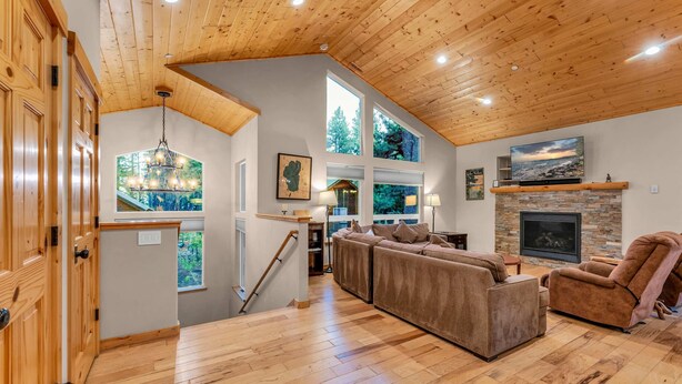 A spacious living room with a wooden ceiling, large windows, a fireplace, and a cozy seating area. - Kings Beach Retreat: Hot Tub, Walk to Beach (Kings Beach)