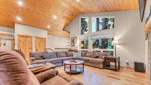 A spacious living room with a wooden ceiling, large windows, and a cozy seating area. - Kings Beach Retreat: Hot Tub, Walk to Beach (Kings Beach)
