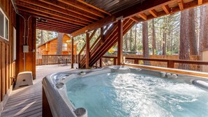 A hot tub on a wooden deck with a view of a cabin in the background. - Kings Beach Retreat: Hot Tub, Walk to Beach (Kings Beach)