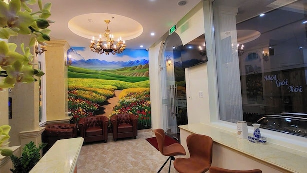 A hotel lobby with a marble floor, a reception desk, leather armchairs, a chandelier, and a mural of a landscape. - Queen Villa 3 Hotel DL - by Bay Luxury (Xuan Huong - Da Lat)