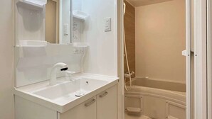 Ein modernes Badezimmer mit Waschbecken, Spiegel und Duschkabine in Weiß.
