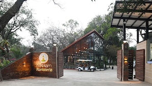 A gated entrance to Neelam Foresteria with a golf cart parked in front. - Neelam Foresteria Resort (Pipariya)
