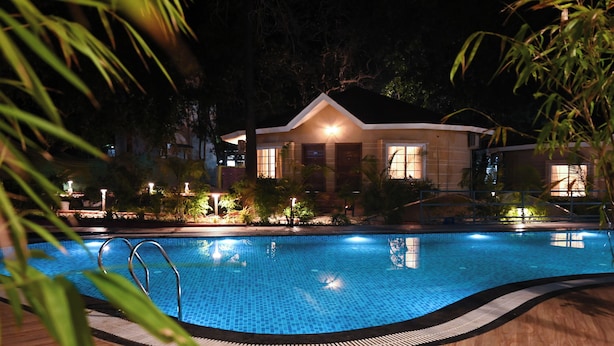 A swimming pool with a tiled edge, surrounded by a wooden deck. - Neelam Foresteria Resort (Pipariya)
