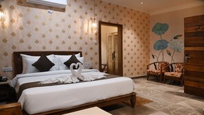A hotel room with a bed, bedside table, lamp, and a wooden wardrobe. - Neelam Foresteria Resort (Pipariya)